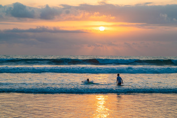 Fototapeta premium KUTA, BALI / INDONESIA - OCTOBER 25, 2018: Children playing in the water on Kuta beach during sunset.