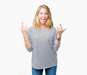 Fototapeta na wymiar Beautiful young woman wearing stripes sweater over isolated background shouting with crazy expression doing rock symbol with hands up. Music star. Heavy concept.
