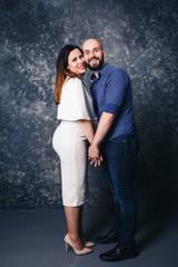 young pregnant couple holding hands and smiling.