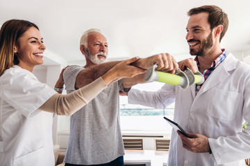 Man having chiropractic arm adjustment. Physiotherapy, sport injury rehabilitation. Senior man exercises in center for chiropractic.