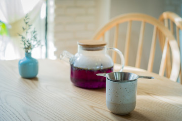 A flower in bottle jar with a teapot on the the wood table in coffee shop.