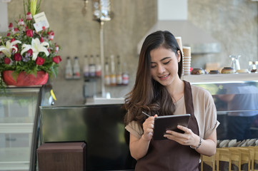 Asian woman working with barista and take it order in coffee cafe with tablet technology.