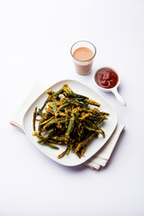 Kurkuri bhindi or crispy ladyfinger or okra fry recipe, served in a bowl with ketchup and hot tea. selective focus