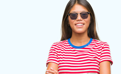 Young asian woman wearing sunglasses over isolated background happy face smiling with crossed arms looking at the camera. Positive person.