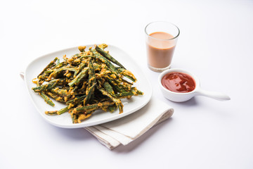 Kurkuri bhindi or crispy ladyfinger or okra fry recipe, served in a bowl with ketchup and hot tea. selective focus