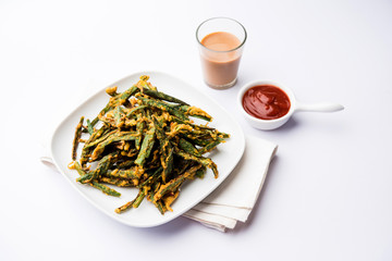 Kurkuri bhindi or crispy ladyfinger or okra fry recipe, served in a bowl with ketchup and hot tea....