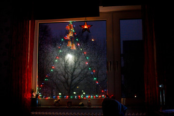 Decorated window with colorful string of fairy lights and a shining star at night