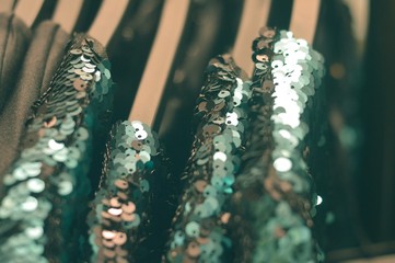 Green shiny dresses on hangers in a store or boutique close-up photo. Winter fashion. Preparing for...