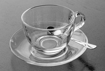 black and white photo of cup on saucer with teaspoon