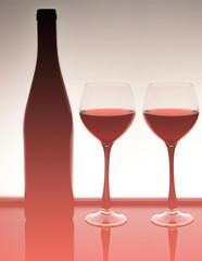 Silhouette of a bottle of wine with two glasses with red wine in the natural color of the living coral - the color of the year 2019