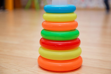 Educational toys for toddlers, gripping rings, isolated on yellow. Colorful Pyramid of Stacked Circular Blocks . Pyramid build from colorful plastic rings, isolated on yellow background.
