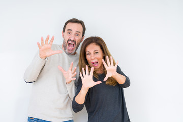 Beautiful middle age couple in love over isolated background afraid and terrified with fear expression stop gesture with hands, shouting in shock. Panic concept.