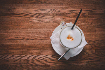 Wooden table plate with a glass of cappuccino white pension and coffee pattern.