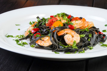 Black squid ink Fettuccine pasta with prawns or shrimps cherry tomatoes, parsley, chili in wine and butter sauce.
