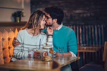  Beautiful loving couple sitting in a cafe drinking coffee and conversating. Love and romance concept.