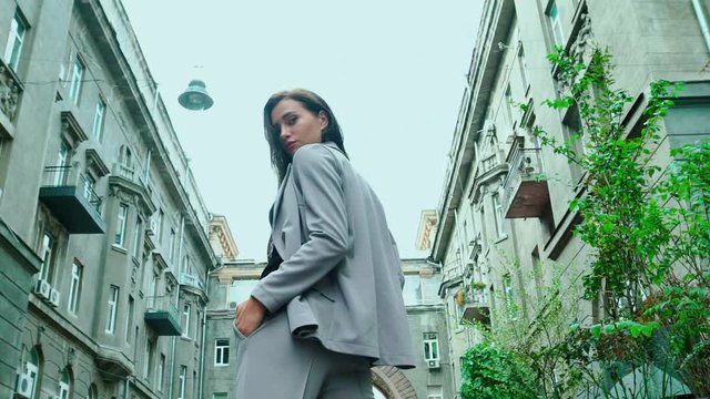 Stylishly dressed brunette model girl posing on the streets of the megalopolis, beautiful girl in a fur coat, waistcoat running on camera, slow motion, autumn time fashion show on the street