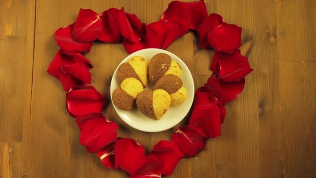 The girl puts in the middle of the heart of rose petal cookies in a white plate