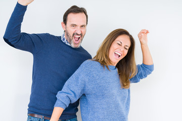 Fototapeta premium Beautiful middle age couple in love over isolated background Dancing happy and cheerful, smiling moving casual and confident listening to music