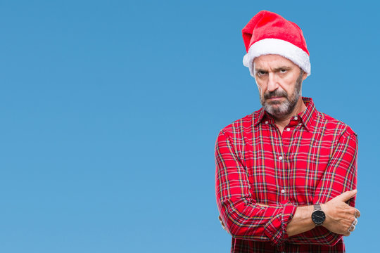 Middle age hoary senior man wearing christmas hat over isolated background skeptic and nervous, disapproving expression on face with crossed arms. Negative person.
