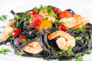 Black squid ink Fettuccine pasta with prawns or shrimps cherry tomatoes, parsley, chili in wine and butter sauce.