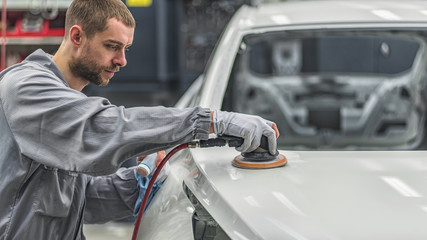 A worker in the painting shop of a car body, sanding painted items