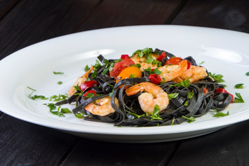 Black squid ink Fettuccine pasta with prawns or shrimps cherry tomatoes, parsley, chili in wine and butter sauce.