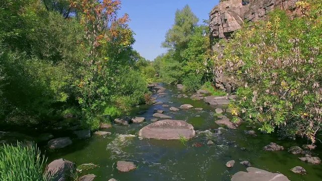 mountain river in canyon, flying over buky canyon in the autumn, big stones in the autumn river, waterfall in autumn colors with big stones