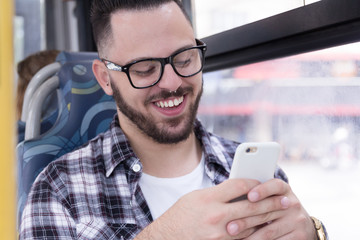 Mobility, communication, social media concept. Student wearing glasses using smart phone while on his commute in city bus.