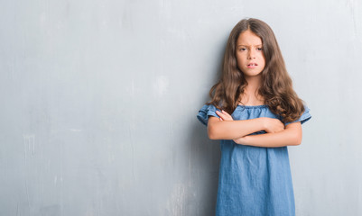 Young hispanic kid over grunge grey wall skeptic and nervous, disapproving expression on face with crossed arms. Negative person.