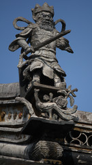King or emperor´s stone carving image on a roof top of a historc building in an old town in China, Asia