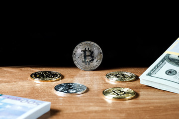 various cryptocurrencies are scattered on the table on top of a pack of dollars, they are covered with drops of water