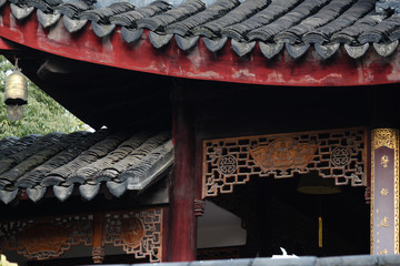Chinese traditional and buddhist temple building showing the roof with old tiles and a symbolic wood carving artwork in China, Asia