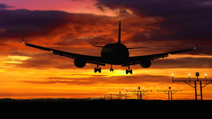 Fototapeta na wymiar Airplane silhouette landing on red sky background