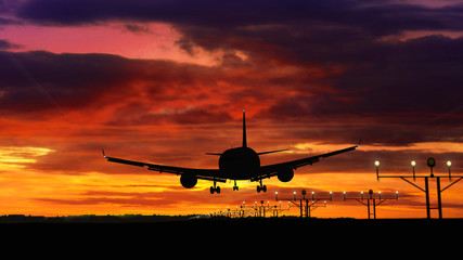 Fototapeta na wymiar Airplane silhouette landing on red sky background