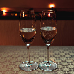 The two glasses of champagne on a golden table on the background of lights