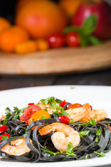 Black squid ink Fettuccine pasta with prawns or shrimps cherry tomatoes, parsley, chili in wine and butter sauce.