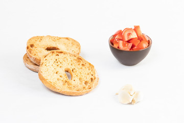 Freselle or friselle, bread typical of the ancient tradition of southern Italy. The picture shows some slices with a central hole, a cup of tomatoes and some garlic Copyspace