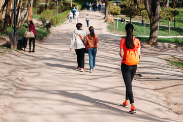 girl tourist in orange t-shirt walking with backpack in Park on road