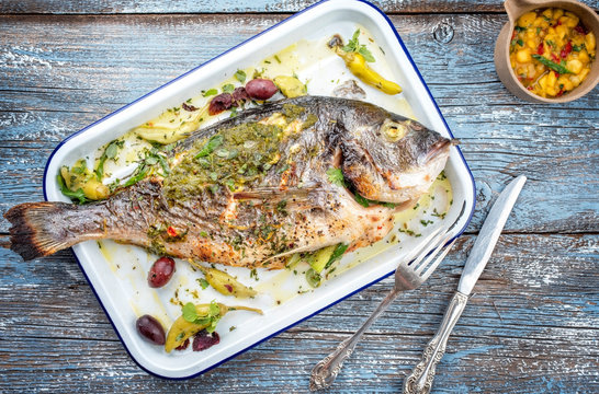 Fresh barbecue gilthead seabream with mango chutney and pesto as top view in a white skillet