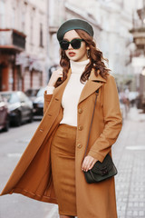 Outdoor portrait of young beautiful fashionable woman wearing trendy autumn coat, turtleneck,...