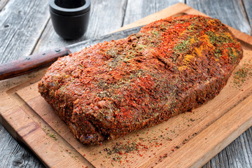 Traditional raw pulled pork piece of Bosten butt with spicy rub as closeup on a wooden cutting board - obrazy, fototapety, plakaty