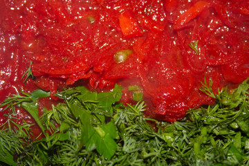 Cut green spicinesses on a background tomato soup..