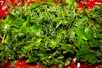 Cut green spicinesses on a background tomato soup..