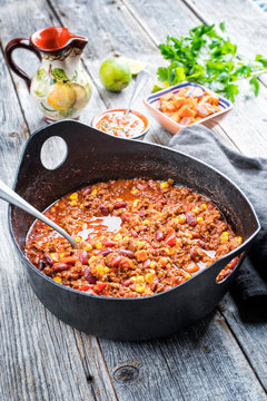 Traditional slow cooked Mexican chili con cane with mincemeat, beans and corn as top view in a modern design cast-iron roasting dish