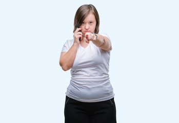 Young adult woman with down syndrome taking using smartphone over isolated background pointing with finger to the camera and to you, hand sign, positive and confident gesture from the front