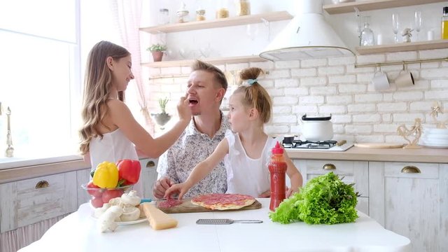 Father and daughters having a fun in the kitchen and making pizza