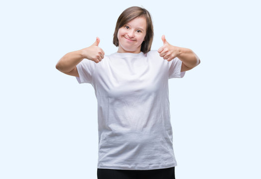 Young adult woman with down syndrome over isolated background success sign doing positive gesture with hand, thumbs up smiling and happy. Looking at the camera with cheerful expression