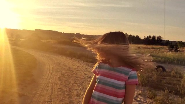 Litttle girl wawing her long hair at sunset, slow motion in retro style