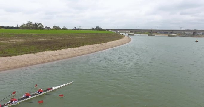 Areal footage flying near a rowing team on a river dressed in red. Rowing Traianus Regatta. 4k video