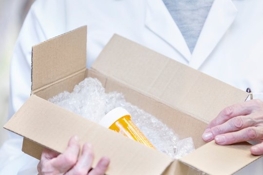 Pharmacist opening box containing medicine